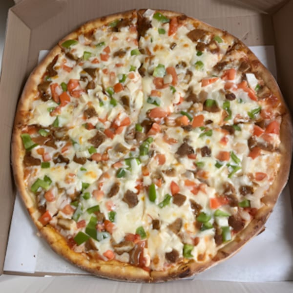 Familia Pizza's large pizza with white cheese, green peppers, red tomatoes, and meat in a box.