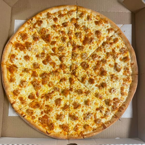 A Familia Pizza buffalo chicken pizza, cut into slices, in a cardboard box.