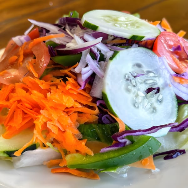A vibrant side salad from Familia Pizza, with shredded carrots, cucumbers, tomatoes, and red cabbage.