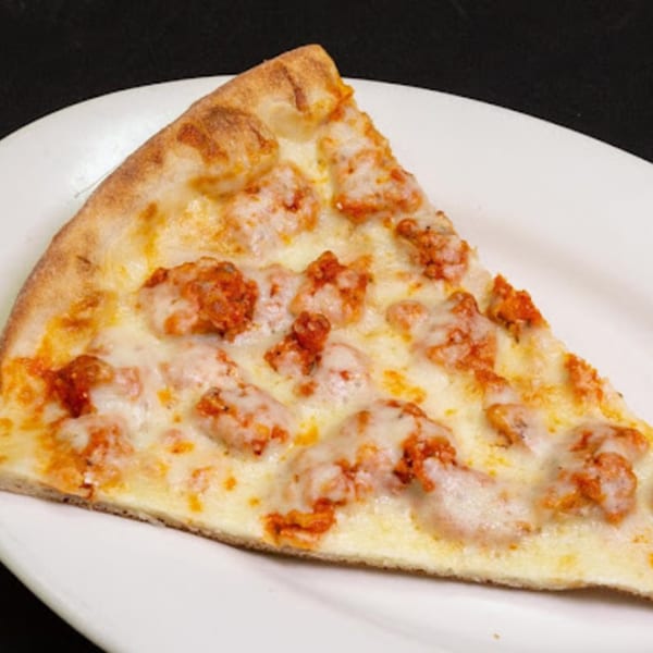 A slice of Familia Pizza's chicken pizza with melted mozzarella cheese and crispy chicken pieces.