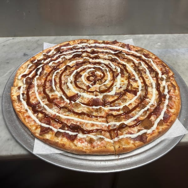 Familia Pizza's BBQ chicken pizza with a spiral of white and brown sauces on a metal tray.